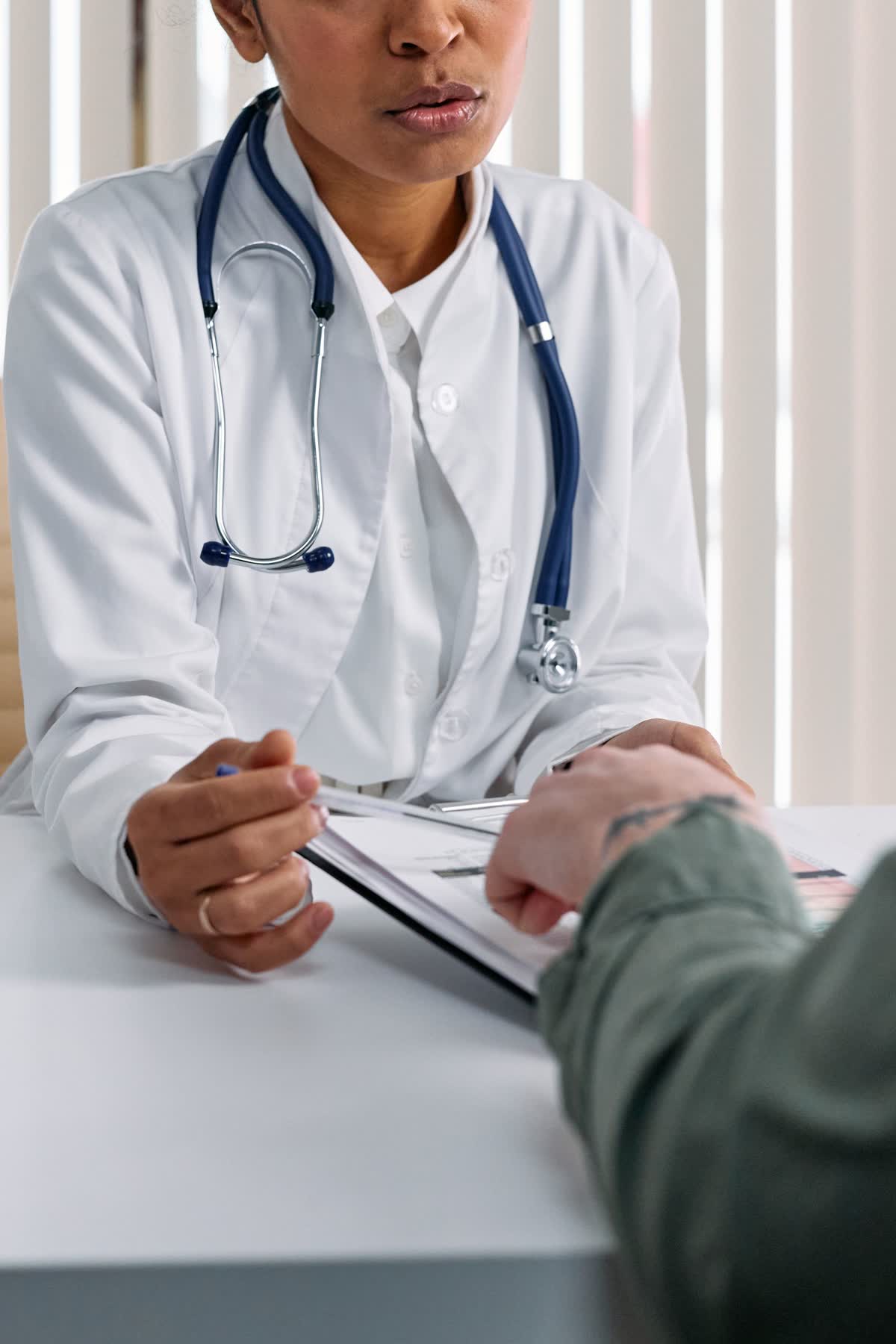 A doctor walking a patient through a consultation document across a desk